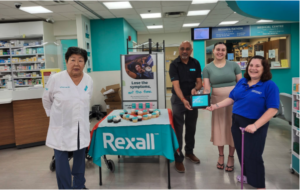 Image description: At a Rexall store location, representatives from the Rexall Care Network present Julia Leonetti (Recreational Respite, Team Member) and Shauna Beaudoin (Hydrocephalus Canada, Director of Programs and Information) with a plaque representing the generous financial support of this initiative.  